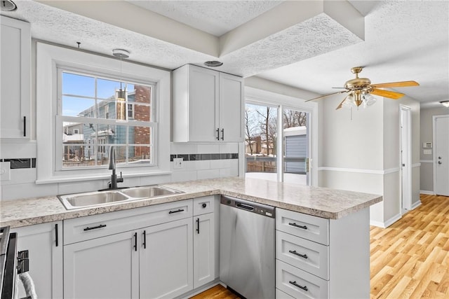 kitchen featuring dishwasher, a textured ceiling, a peninsula, and a sink