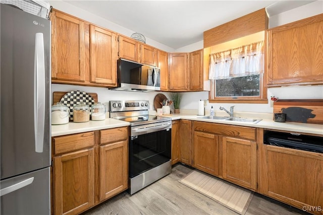 kitchen featuring a sink, light wood finished floors, appliances with stainless steel finishes, and light countertops