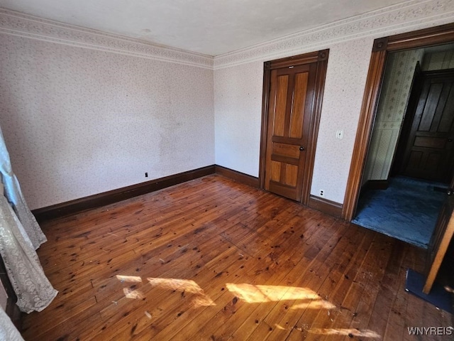 unfurnished bedroom featuring wallpapered walls, baseboards, wood-type flooring, and ornamental molding