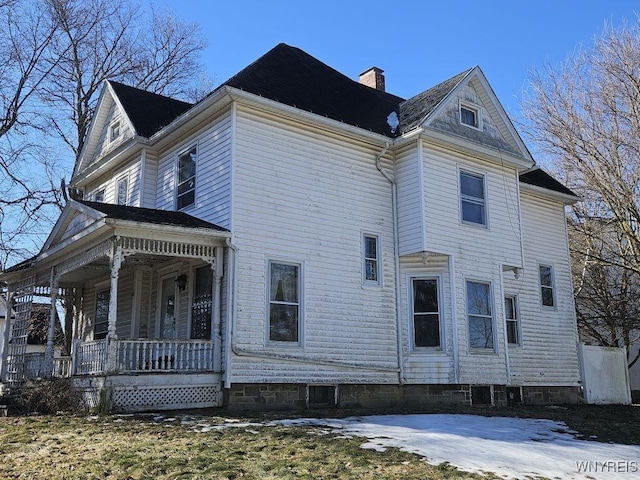 view of side of property with a porch and a chimney