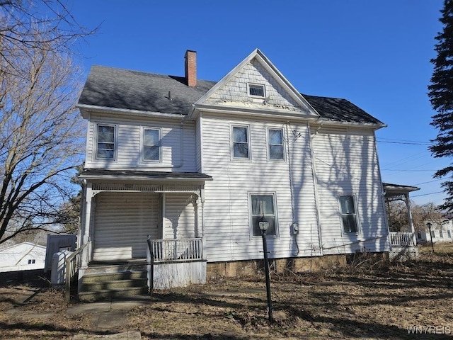 view of front facade featuring covered porch and a chimney