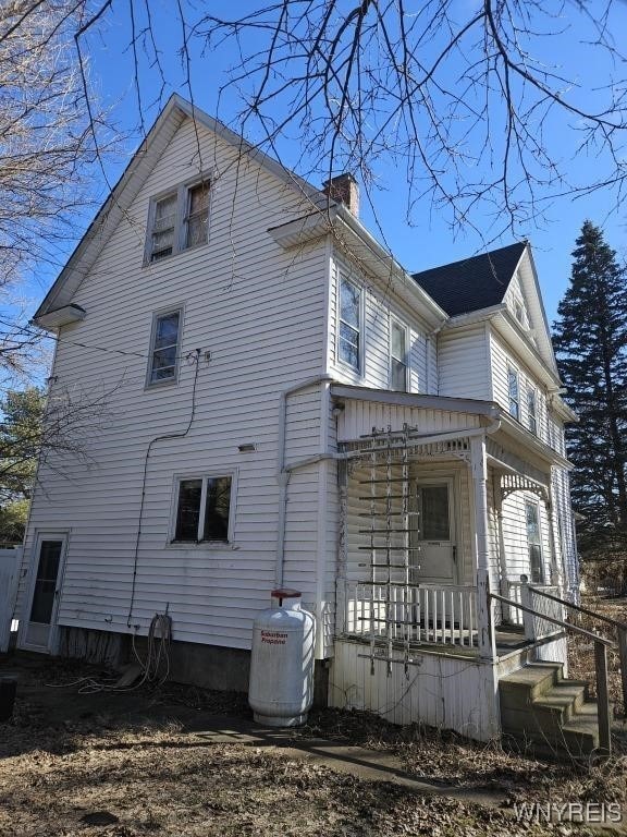 view of side of property with a porch and a chimney