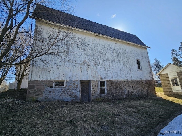 view of home's exterior with stone siding and a shingled roof