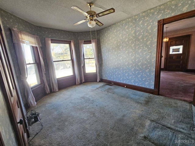 empty room with wallpapered walls, carpet, baseboards, and a textured ceiling