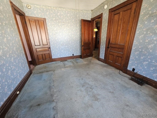 empty room with carpet flooring, wallpapered walls, and baseboards