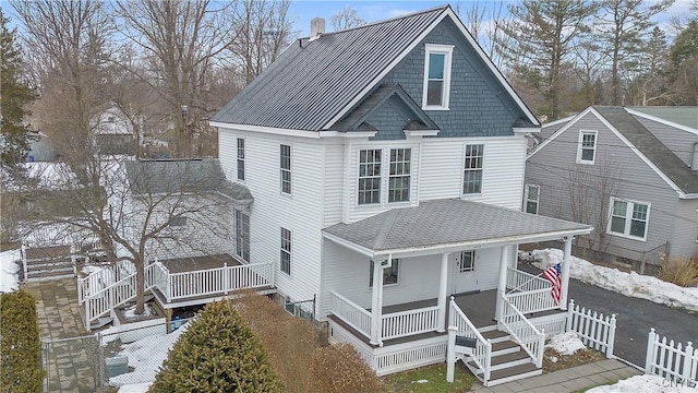 view of front of home with a porch, fence, roof with shingles, and a chimney