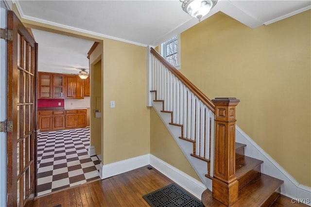 stairway with hardwood / wood-style floors, crown molding, visible vents, and baseboards