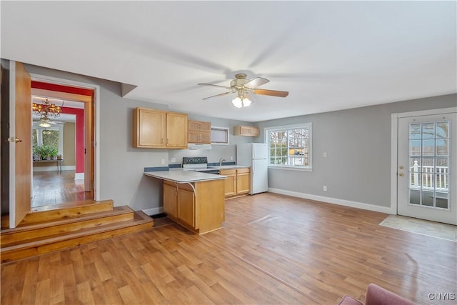 kitchen with a peninsula, light wood-style flooring, electric range oven, and freestanding refrigerator