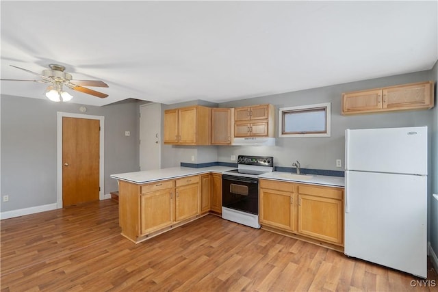 kitchen with electric stove, a sink, freestanding refrigerator, a peninsula, and light wood finished floors