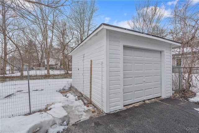 snow covered garage featuring a garage and fence