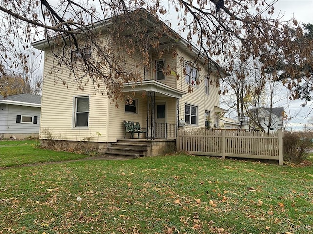 rear view of property featuring a lawn and covered porch