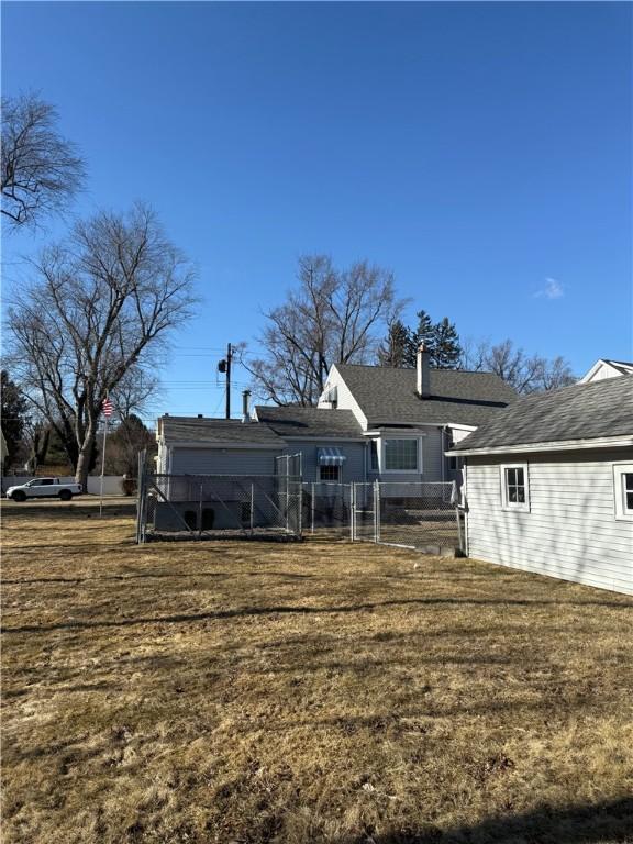 back of house with a gate, a yard, a chimney, and fence