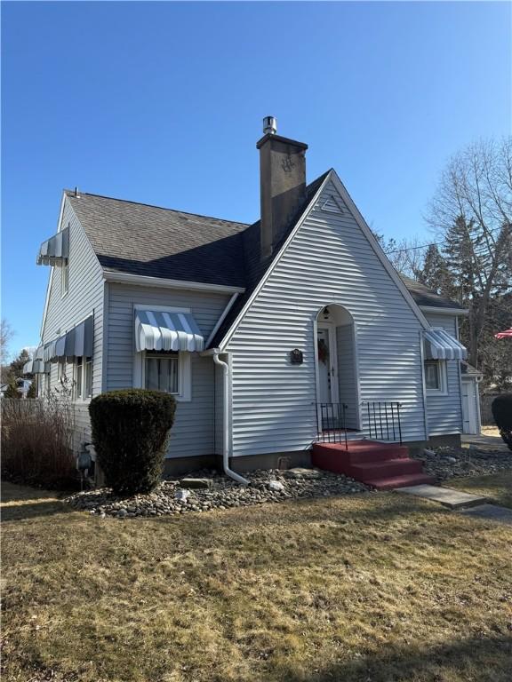 back of property with a chimney and a yard