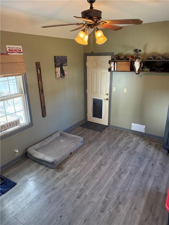 unfurnished bedroom featuring ceiling fan, visible vents, baseboards, and wood finished floors