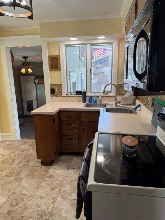 kitchen featuring black microwave, light countertops, ornamental molding, electric stove, and a sink