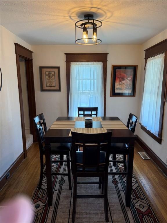 dining area featuring dark wood-style floors, visible vents, and baseboards