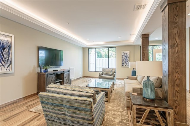 living room featuring visible vents, light wood-style flooring, baseboards, and a tray ceiling