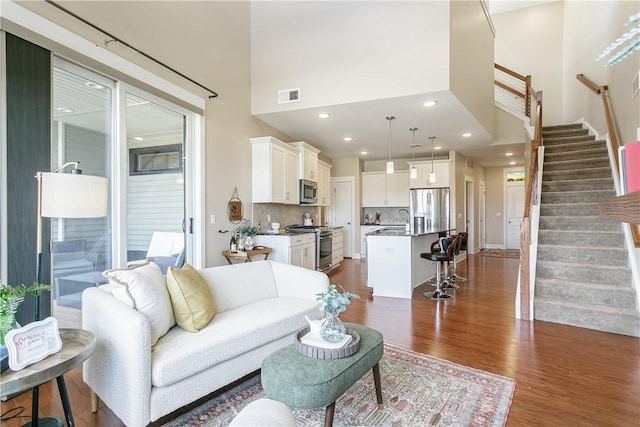 living area with visible vents, stairway, recessed lighting, a high ceiling, and dark wood-style flooring