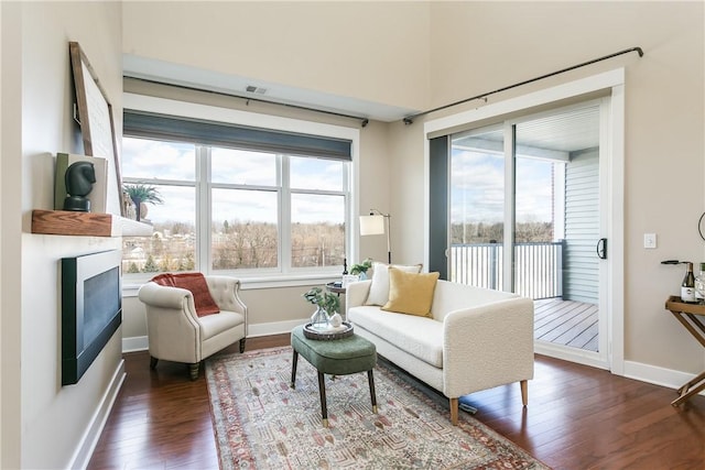 interior space featuring baseboards, dark wood-type flooring, and a glass covered fireplace