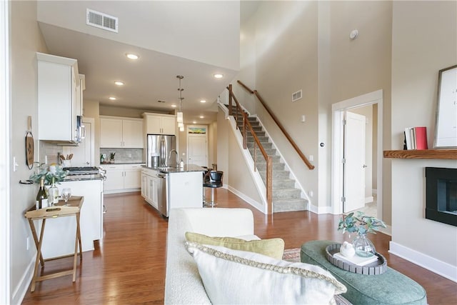 living area with recessed lighting, visible vents, dark wood-style floors, and stairs