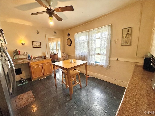 dining space with ceiling fan and baseboards