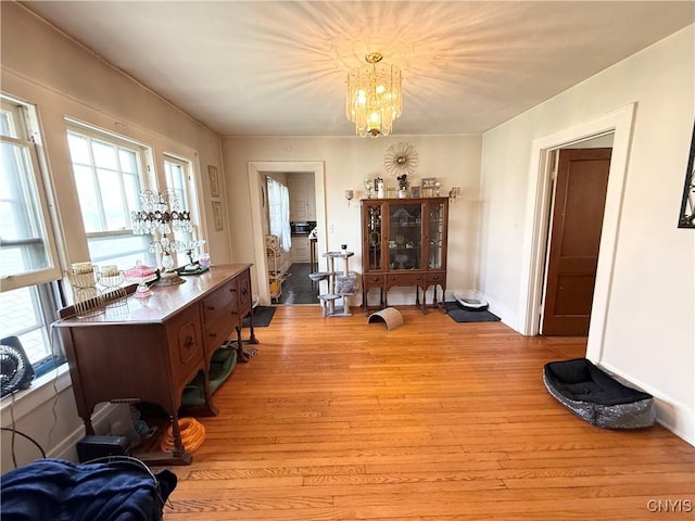 interior space with a wealth of natural light, a notable chandelier, baseboards, and light wood-style floors