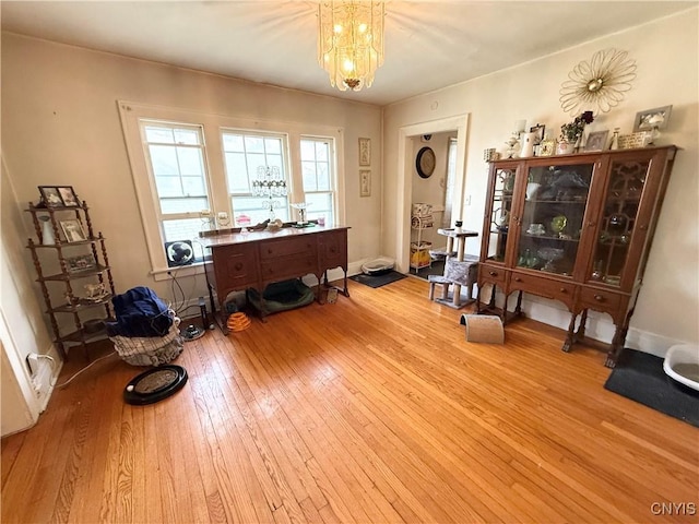 miscellaneous room with a chandelier, baseboards, and wood-type flooring