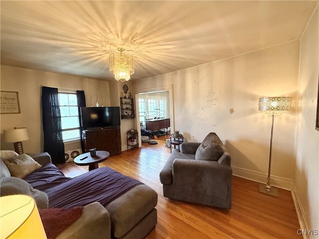 living area with a chandelier, baseboards, and wood finished floors