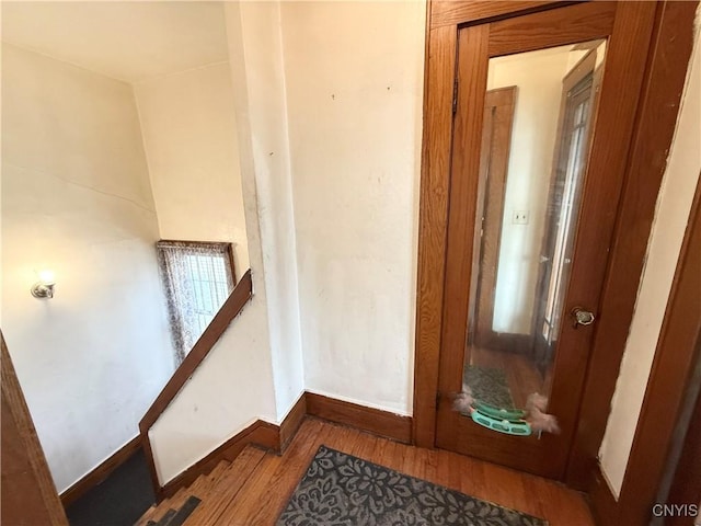 staircase featuring wood finished floors and baseboards