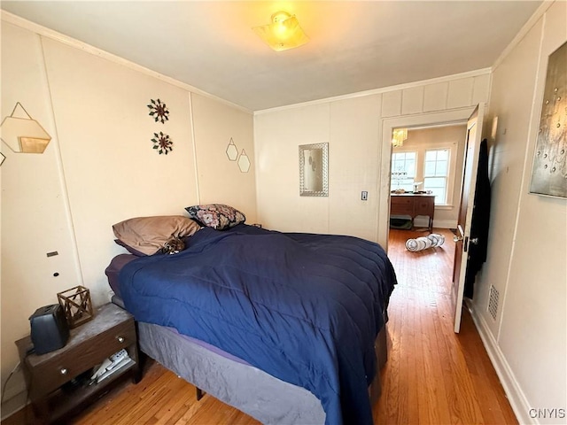 bedroom with crown molding and wood finished floors