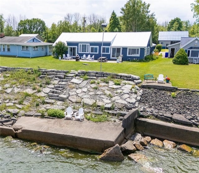 back of property with a lawn, a patio, and a water view