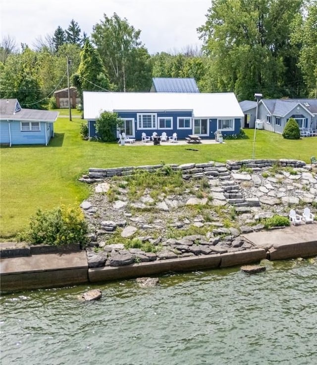 rear view of house with a lawn and a water view