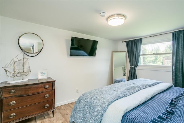 bedroom featuring light wood finished floors and baseboards