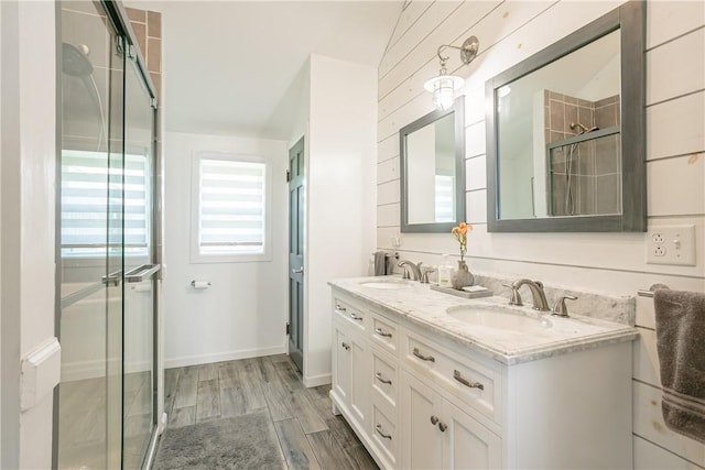 bathroom featuring double vanity, wood finished floors, a stall shower, and a sink