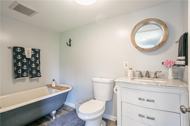 full bathroom featuring visible vents, toilet, baseboards, a freestanding bath, and vanity