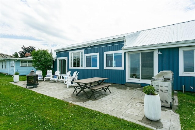 back of property featuring metal roof, a yard, and a patio area