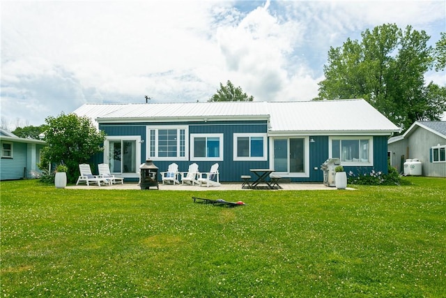 rear view of property with a yard, metal roof, and a patio area