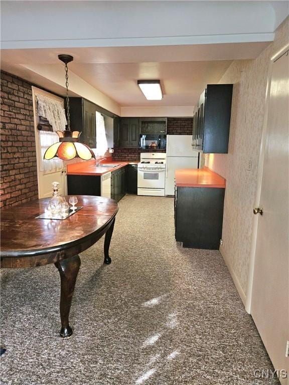 kitchen featuring white appliances, brick wall, and a sink