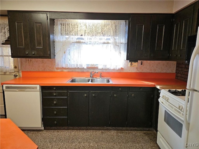 kitchen with a sink, white appliances, dark cabinets, and light countertops