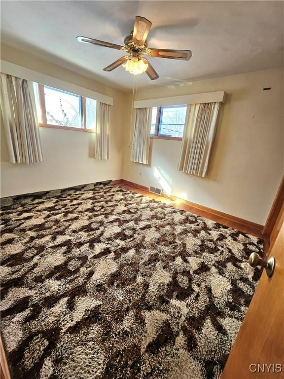 empty room with visible vents, baseboards, and a ceiling fan