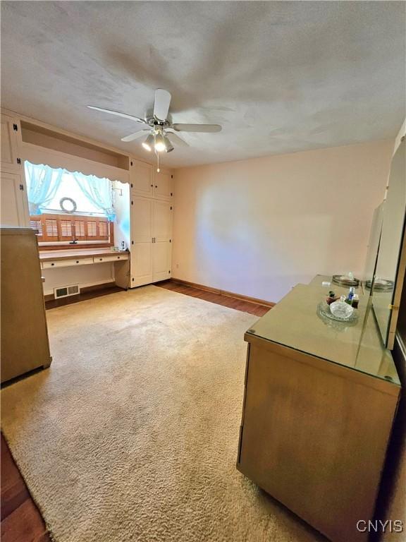 interior space featuring visible vents, baseboards, ceiling fan, light colored carpet, and a textured ceiling