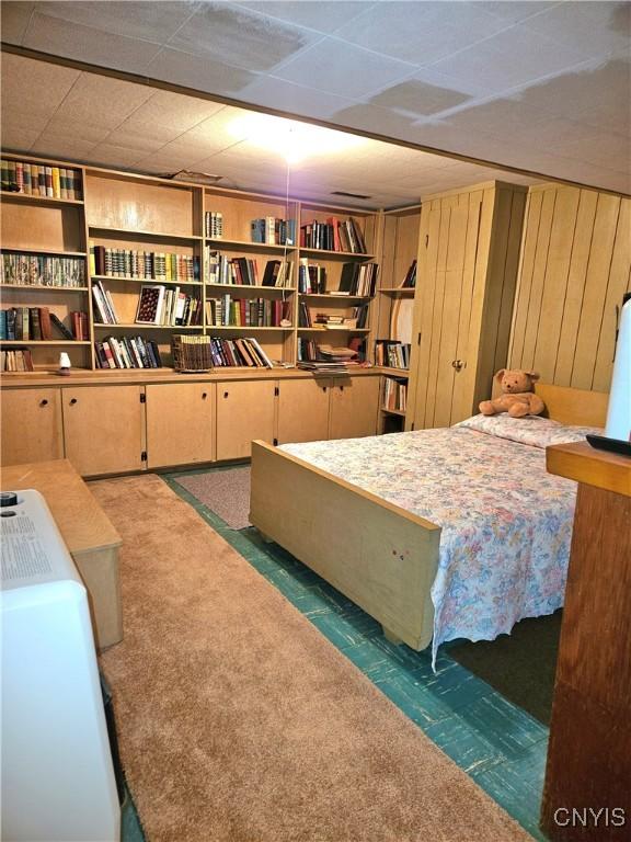 bedroom featuring wood walls and carpet flooring