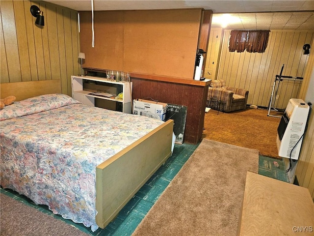 bedroom featuring wooden walls, heating unit, and dark carpet