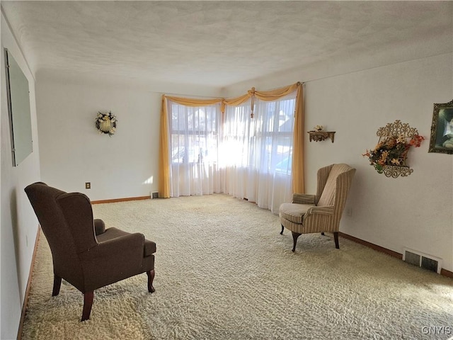 sitting room featuring baseboards, visible vents, carpet floors, and a textured ceiling