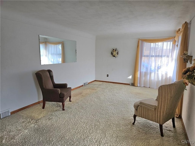 sitting room featuring visible vents, plenty of natural light, and carpet flooring