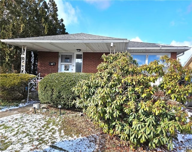 view of front of home featuring brick siding and a shingled roof