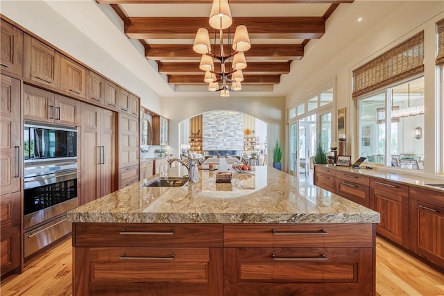 kitchen with oven, built in microwave, a notable chandelier, a warming drawer, and a sink