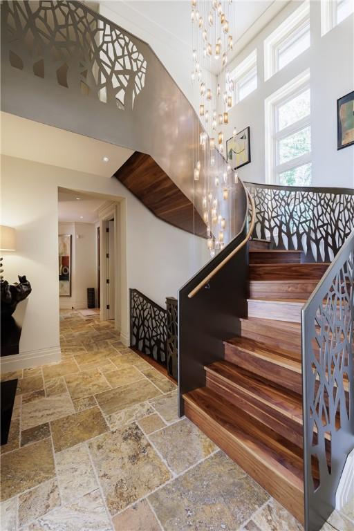 staircase featuring a chandelier, baseboards, and stone tile flooring