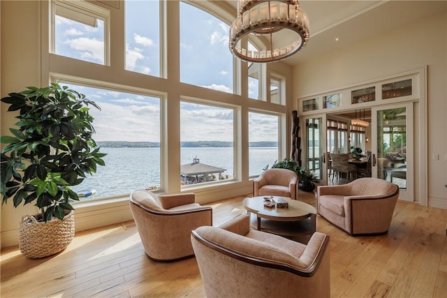 interior space with a high ceiling, light wood-style flooring, and a water view