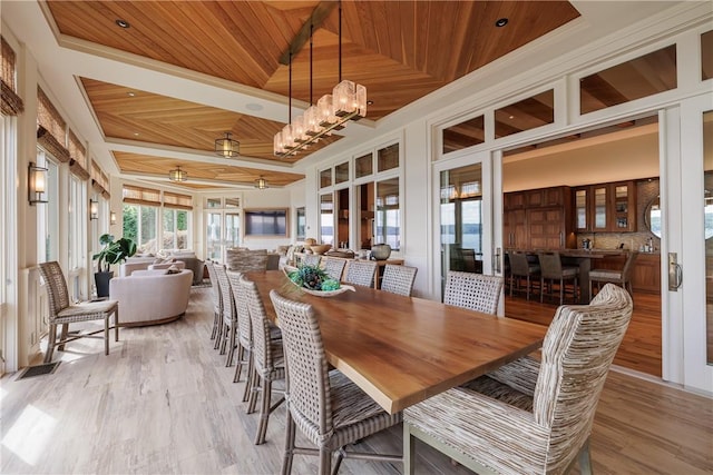 dining space featuring a high ceiling, light wood-style floors, a raised ceiling, wood ceiling, and a chandelier